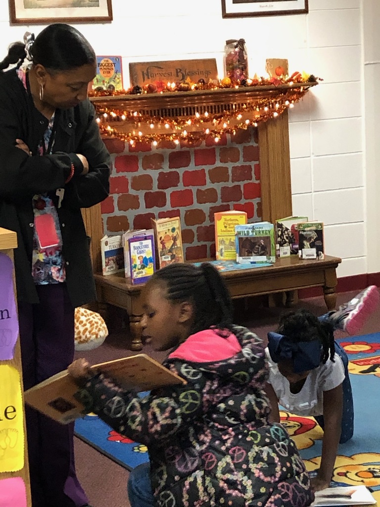 While kindergarten classes visit the library, the teacher assistants listen to students as they find words they know in library books and begin to read. Ms. McMullen is encouraging two students as they tackle reading one of their first books. They are so excited about their accomplishment!